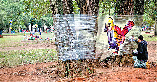 O artista gráfico Binho Ribeiro realiza performance artística usando plástico de isolamento no parque Ibirapuera